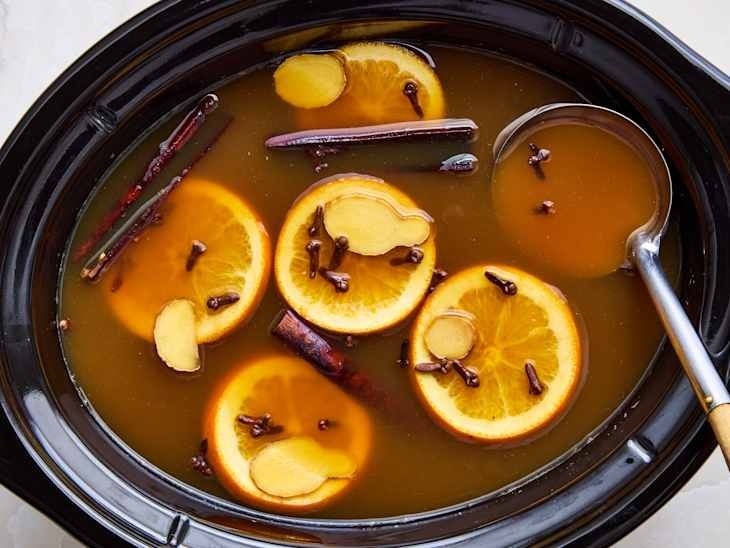 Mulled cider with orange slices, cinnamon, ginger, and cloves in a slow cooker